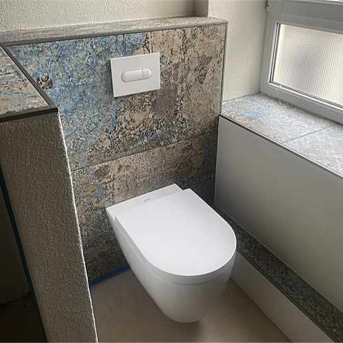 Wand-WC vor Vorwand mit gemusterten Fliesen in Blau- und Sandtönen